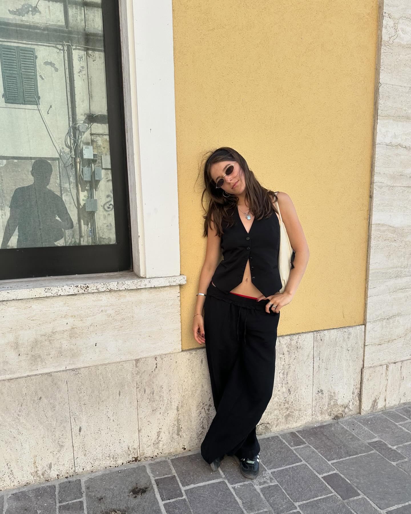 Nina leaning against a yellow wall